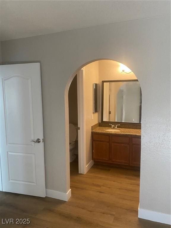 bathroom featuring wood-type flooring, vanity, and toilet