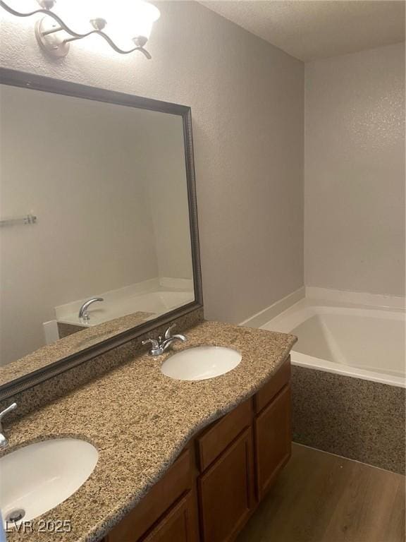 bathroom featuring vanity, wood-type flooring, and tiled bath