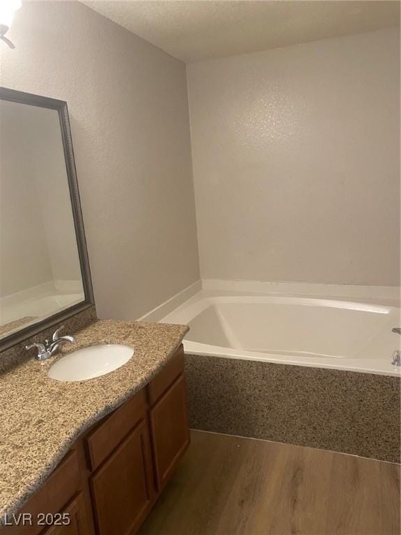 bathroom with hardwood / wood-style floors, vanity, and a bathing tub