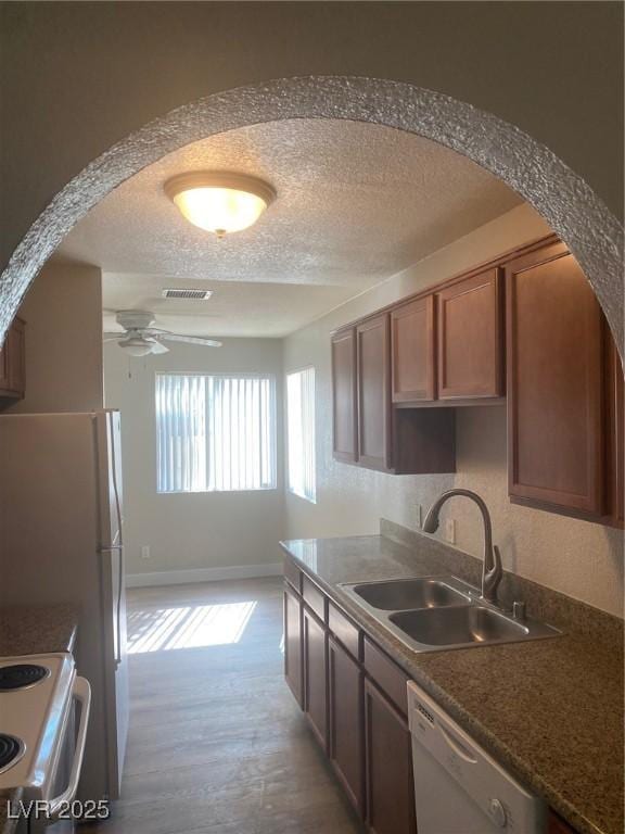 kitchen with ceiling fan, sink, white dishwasher, a textured ceiling, and range