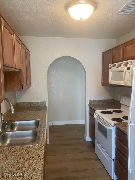 kitchen featuring a textured ceiling, white appliances, dark hardwood / wood-style floors, and sink