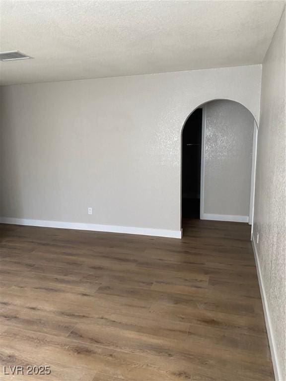 unfurnished room with dark hardwood / wood-style flooring and a textured ceiling