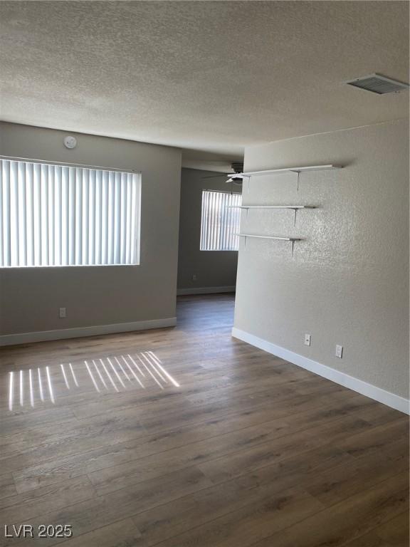 empty room with a textured ceiling and dark wood-type flooring