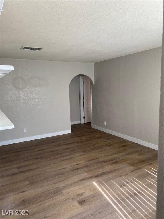 spare room with dark hardwood / wood-style floors and a textured ceiling