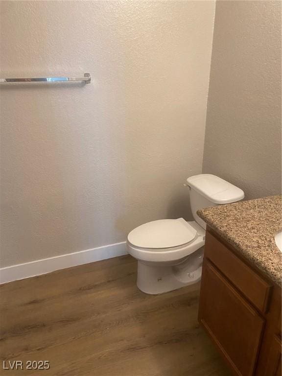 bathroom featuring toilet, vanity, and hardwood / wood-style flooring