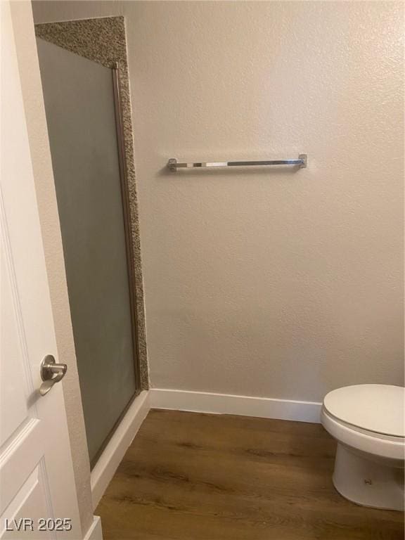 bathroom featuring hardwood / wood-style flooring, toilet, and a shower with shower door