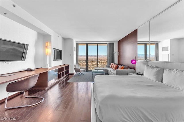 bedroom with hardwood / wood-style flooring and expansive windows