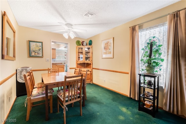 dining room with a textured ceiling, dark carpet, and ceiling fan