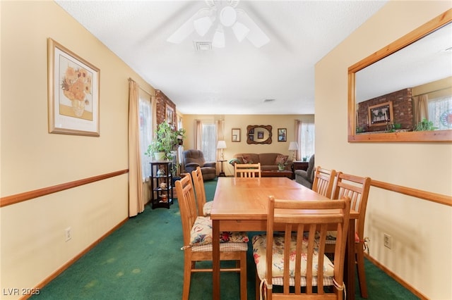 dining space featuring ceiling fan and dark carpet