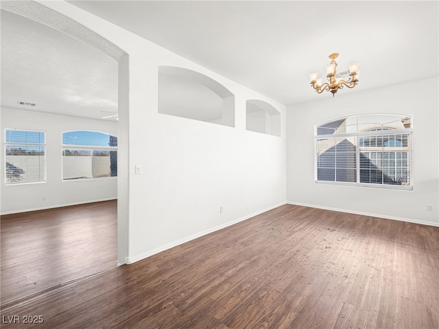 spare room featuring dark hardwood / wood-style flooring and an inviting chandelier