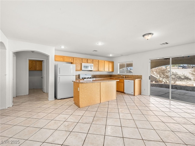 kitchen featuring a center island, light tile patterned floors, white appliances, and sink