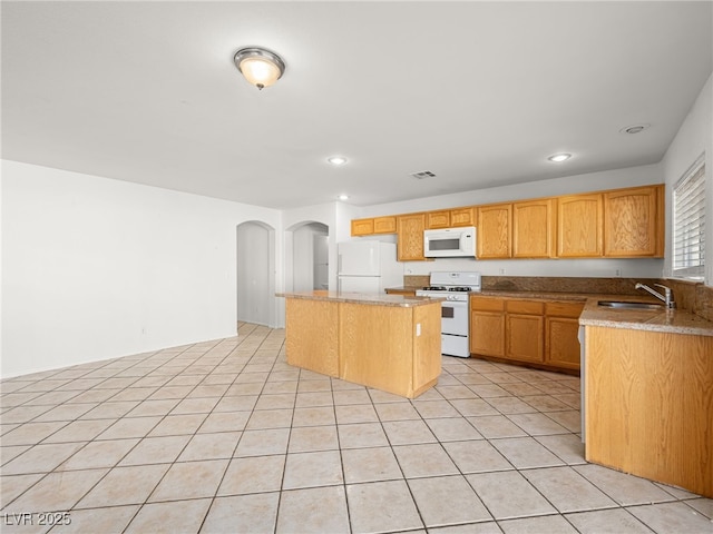 kitchen with light stone counters, white appliances, sink, light tile patterned floors, and a kitchen island