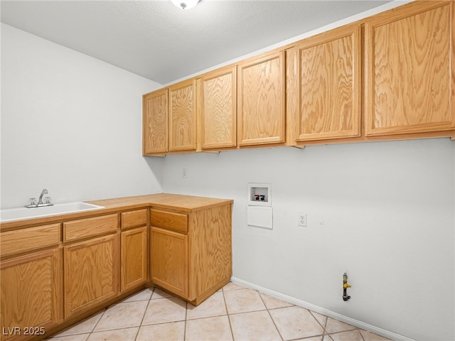 clothes washing area featuring cabinets, sink, light tile patterned floors, and washer hookup