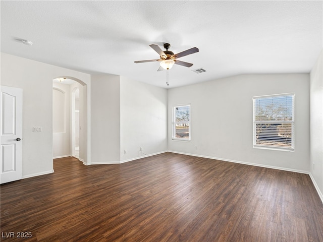 empty room featuring a textured ceiling, dark hardwood / wood-style flooring, vaulted ceiling, and ceiling fan