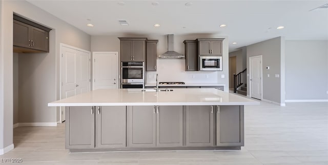 kitchen with appliances with stainless steel finishes, sink, a spacious island, and wall chimney range hood