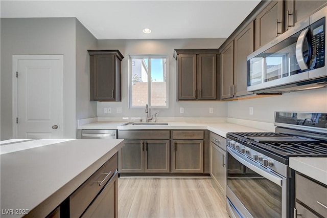 kitchen featuring stainless steel appliances, sink, and light wood-type flooring