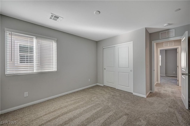 unfurnished bedroom with light carpet and a closet