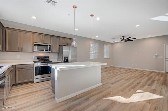 kitchen featuring decorative light fixtures, a center island, light hardwood / wood-style flooring, ceiling fan, and stainless steel appliances