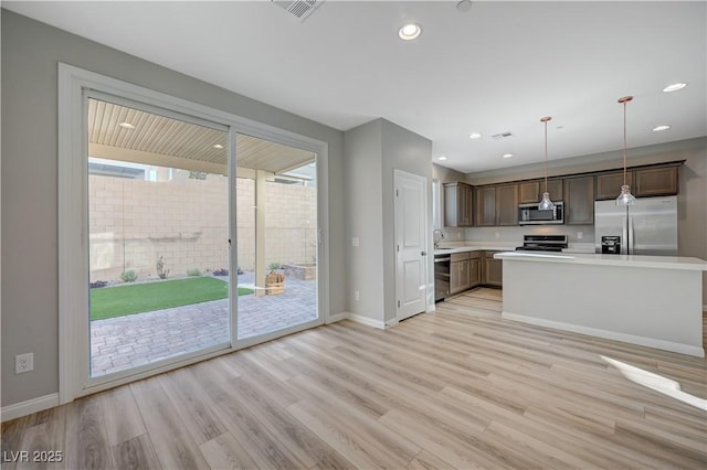 kitchen featuring pendant lighting, stainless steel appliances, sink, and light hardwood / wood-style flooring