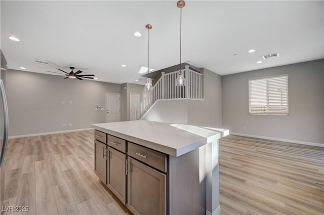 kitchen featuring hanging light fixtures, a center island, ceiling fan, and light hardwood / wood-style flooring