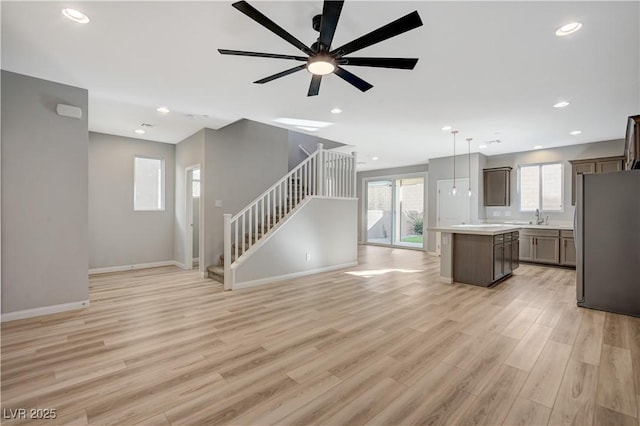 unfurnished living room with sink, light hardwood / wood-style floors, and ceiling fan