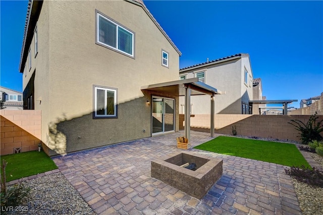 rear view of property with a patio area and a fire pit