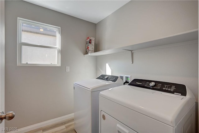 laundry room with washing machine and clothes dryer and light wood-type flooring