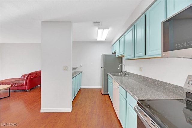 kitchen with blue cabinets, sink, appliances with stainless steel finishes, and light hardwood / wood-style flooring