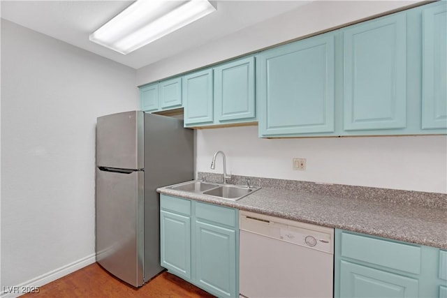 kitchen with stainless steel fridge, light wood-type flooring, white dishwasher, sink, and blue cabinetry