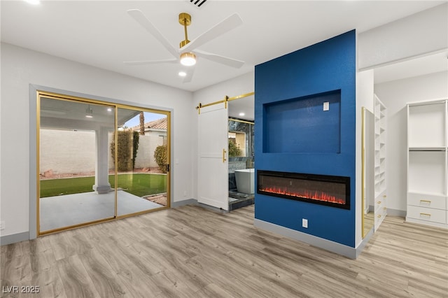 interior space featuring a fireplace, light wood-type flooring, and ceiling fan