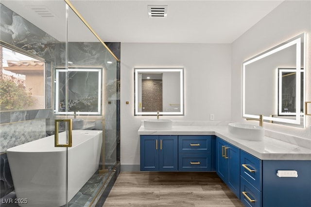 bathroom with a washtub, vanity, and wood-type flooring