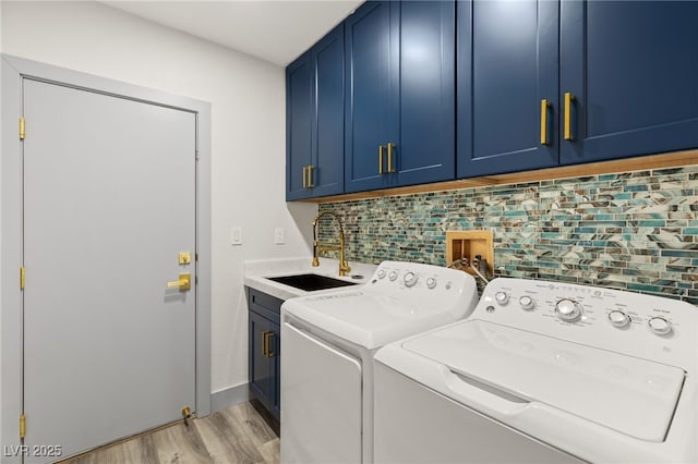 clothes washing area with separate washer and dryer, sink, cabinets, and light wood-type flooring