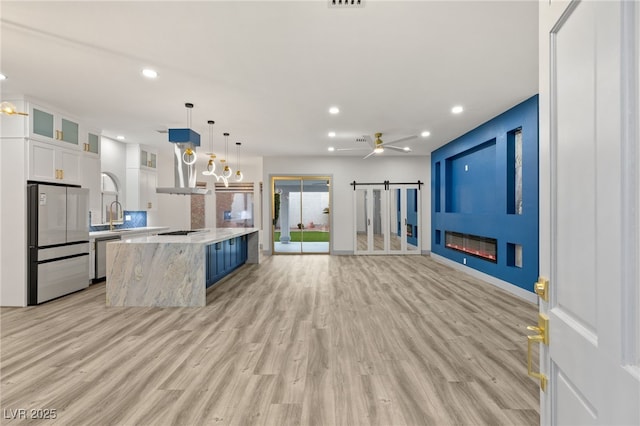 kitchen with pendant lighting, a center island, a barn door, white cabinetry, and stainless steel appliances