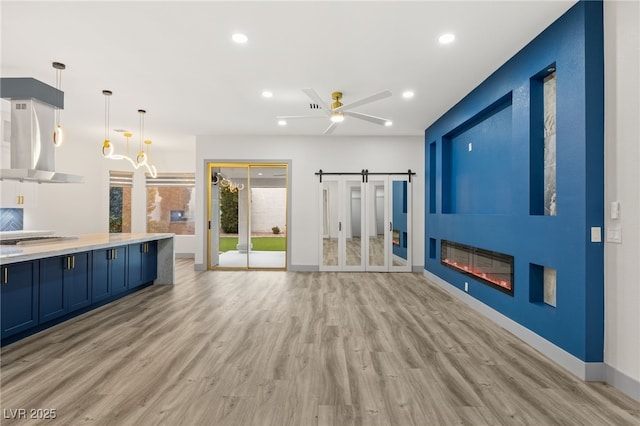 interior space with a barn door, ceiling fan, and light hardwood / wood-style flooring