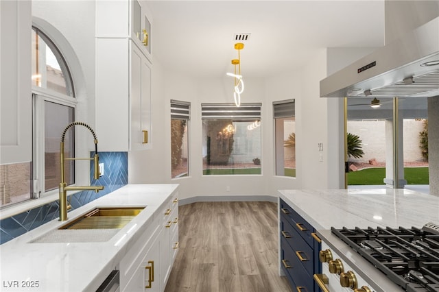 kitchen with white cabinets, light stone counters, and sink