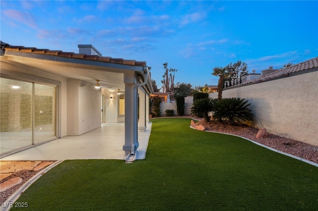 yard at dusk featuring a patio