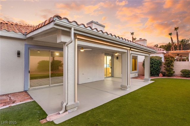 back house at dusk with a lawn and a patio