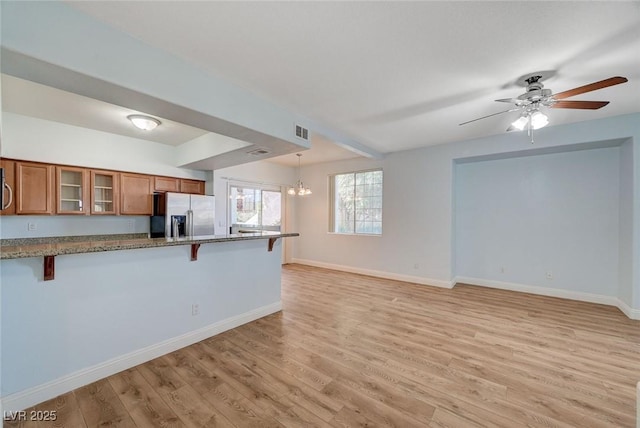 1701 King James St Unit 101, Las Vegas, NV 89144 - kitchen with stainless steel appliances, brown cabinetry, a breakfast bar, glass insert cabinets, and light wood-style flooring