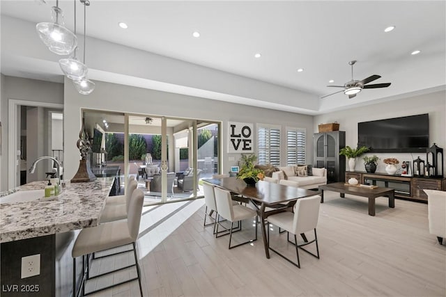 dining space with ceiling fan, light hardwood / wood-style floors, and sink