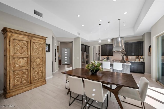 dining space featuring light wood-type flooring and a raised ceiling