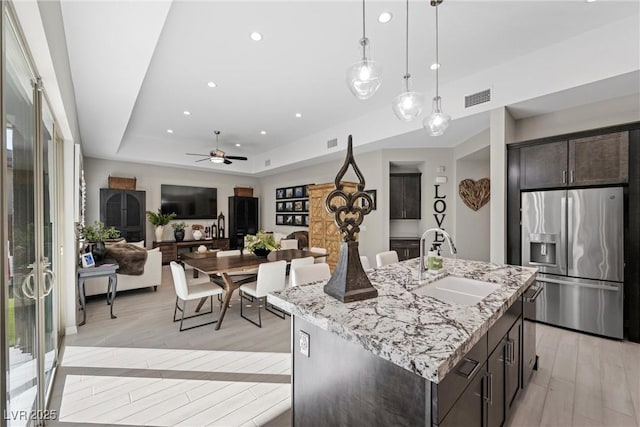 kitchen featuring a center island with sink, sink, ceiling fan, appliances with stainless steel finishes, and dark brown cabinetry