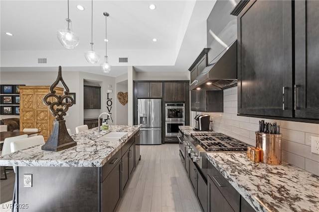 kitchen featuring sink, stainless steel appliances, backsplash, a breakfast bar, and a center island with sink