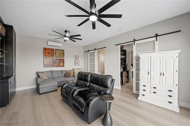 living room featuring ceiling fan, a barn door, light hardwood / wood-style floors, and a wall mounted AC