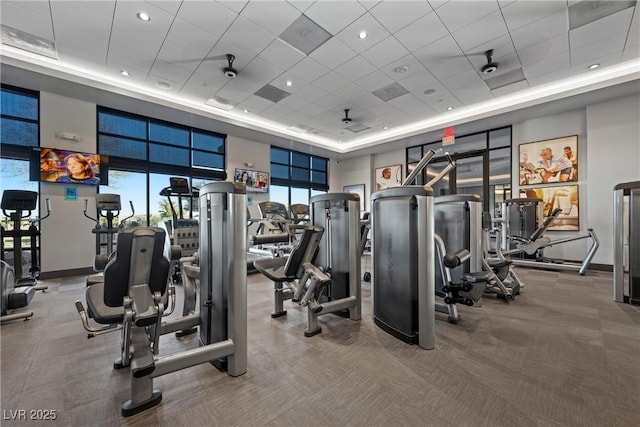 gym featuring carpet, a towering ceiling, and a paneled ceiling