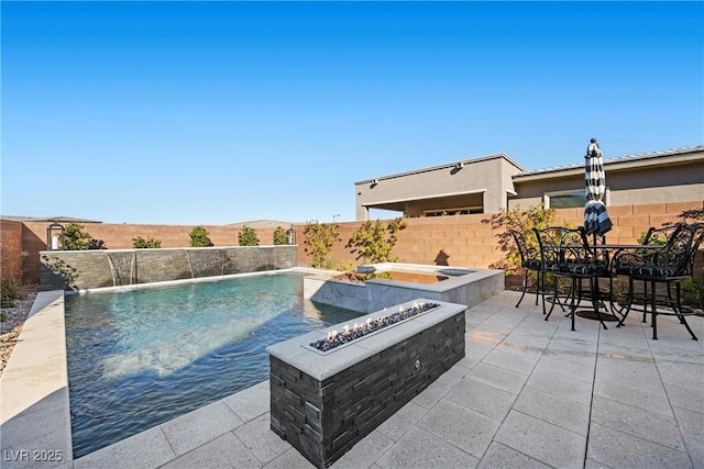 view of pool featuring a mountain view, pool water feature, an in ground hot tub, a patio, and an outdoor fire pit