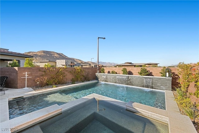 view of pool with pool water feature, a mountain view, and an in ground hot tub