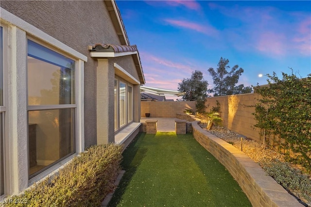 yard at dusk featuring a patio