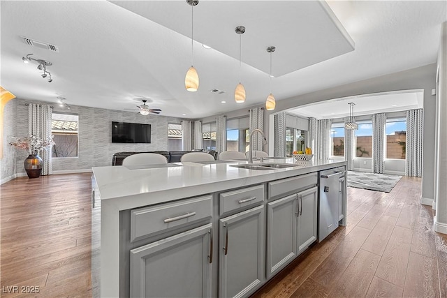 kitchen featuring decorative light fixtures, ceiling fan, sink, and an island with sink