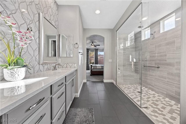 bathroom featuring a tile shower, ceiling fan, vanity, and a healthy amount of sunlight