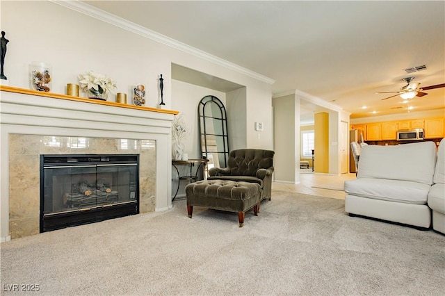 carpeted living room with a premium fireplace, crown molding, and ceiling fan